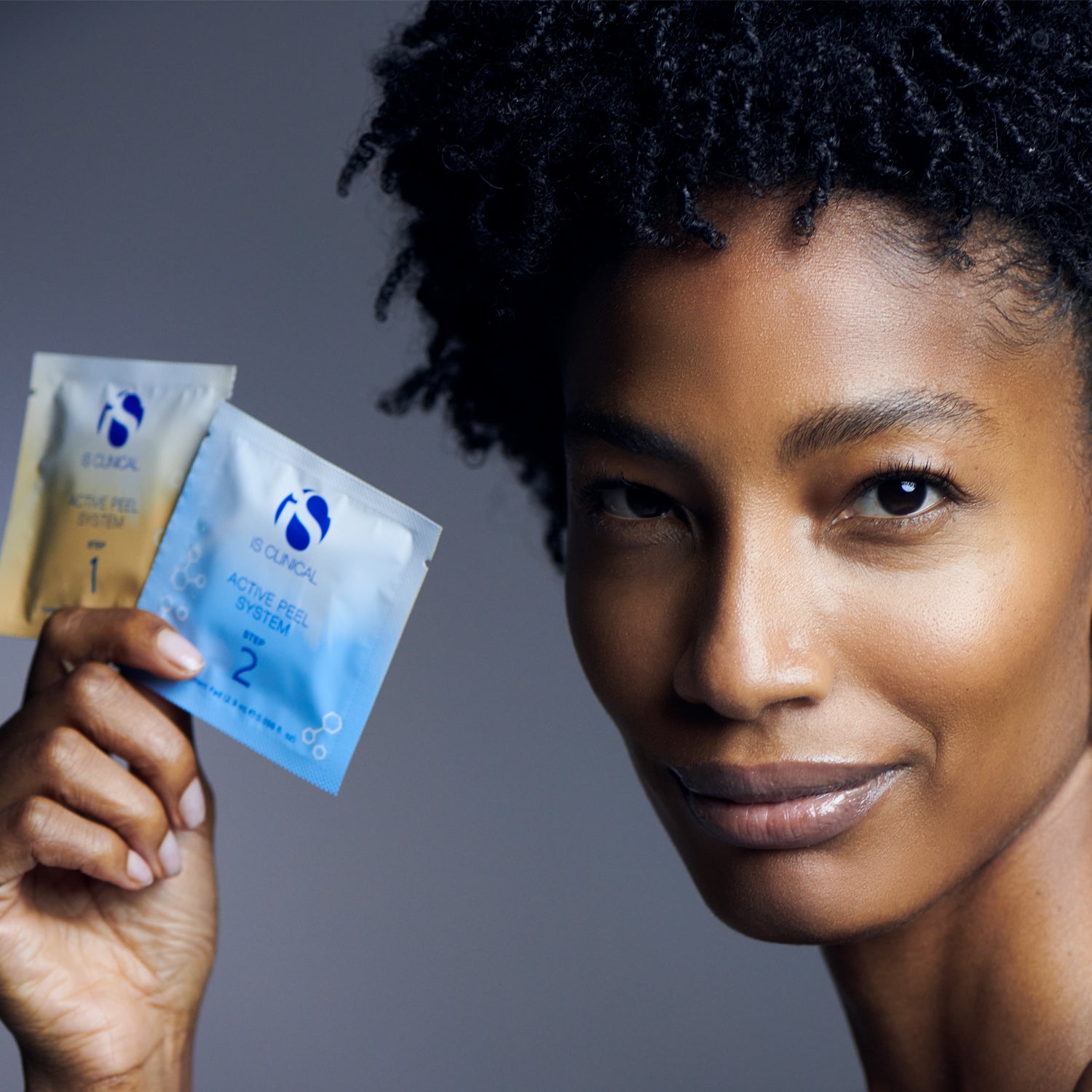 A woman holding two packets of Active Peel System by MK Aesthetics, showcasing a smooth, youthful complexion.