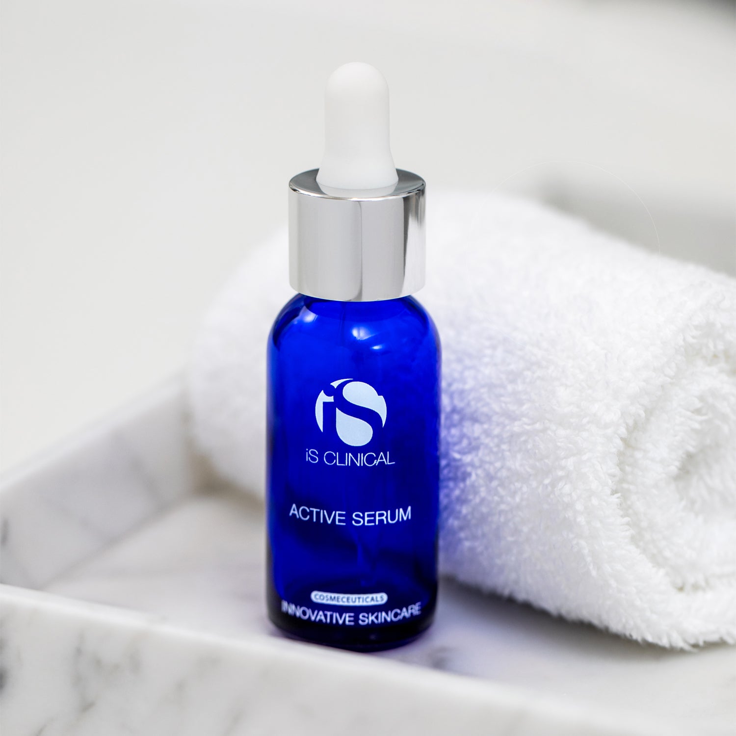 iS Clinical Active Serum bottle on a marble counter with a white towel, featuring MK Aesthetics branding.