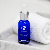 iS Clinical Active Serum bottle on a marble counter with a white towel, featuring MK Aesthetics branding.