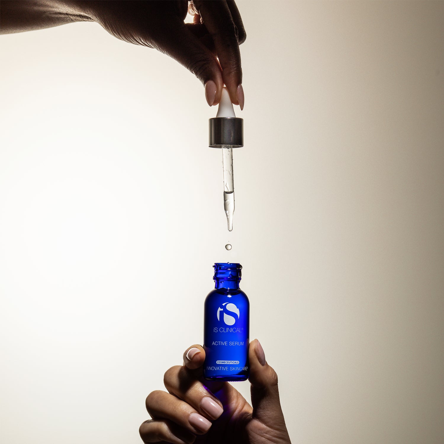 Hands holding a dropper above a blue bottle of Active Serum from MK Aesthetics, designed for effective skincare.