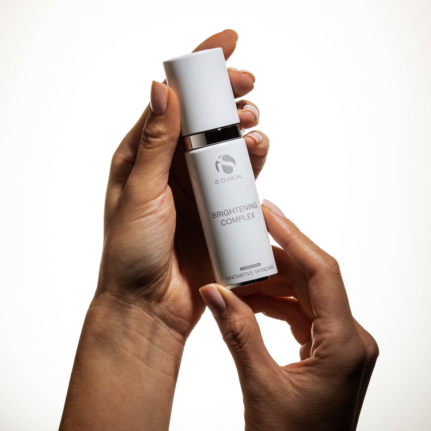 Person holding a bottle of Brightening Complex, a skincare product by MK Aesthetics for hydration and antioxidant benefits.