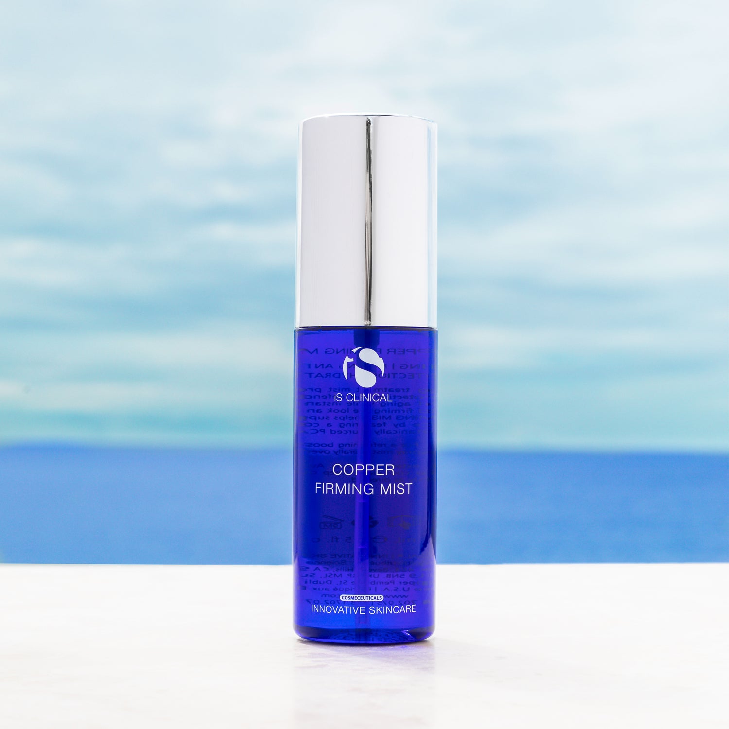 Copper Firming Mist bottle with silver cap against a blue sky background, designed for antioxidant skincare.