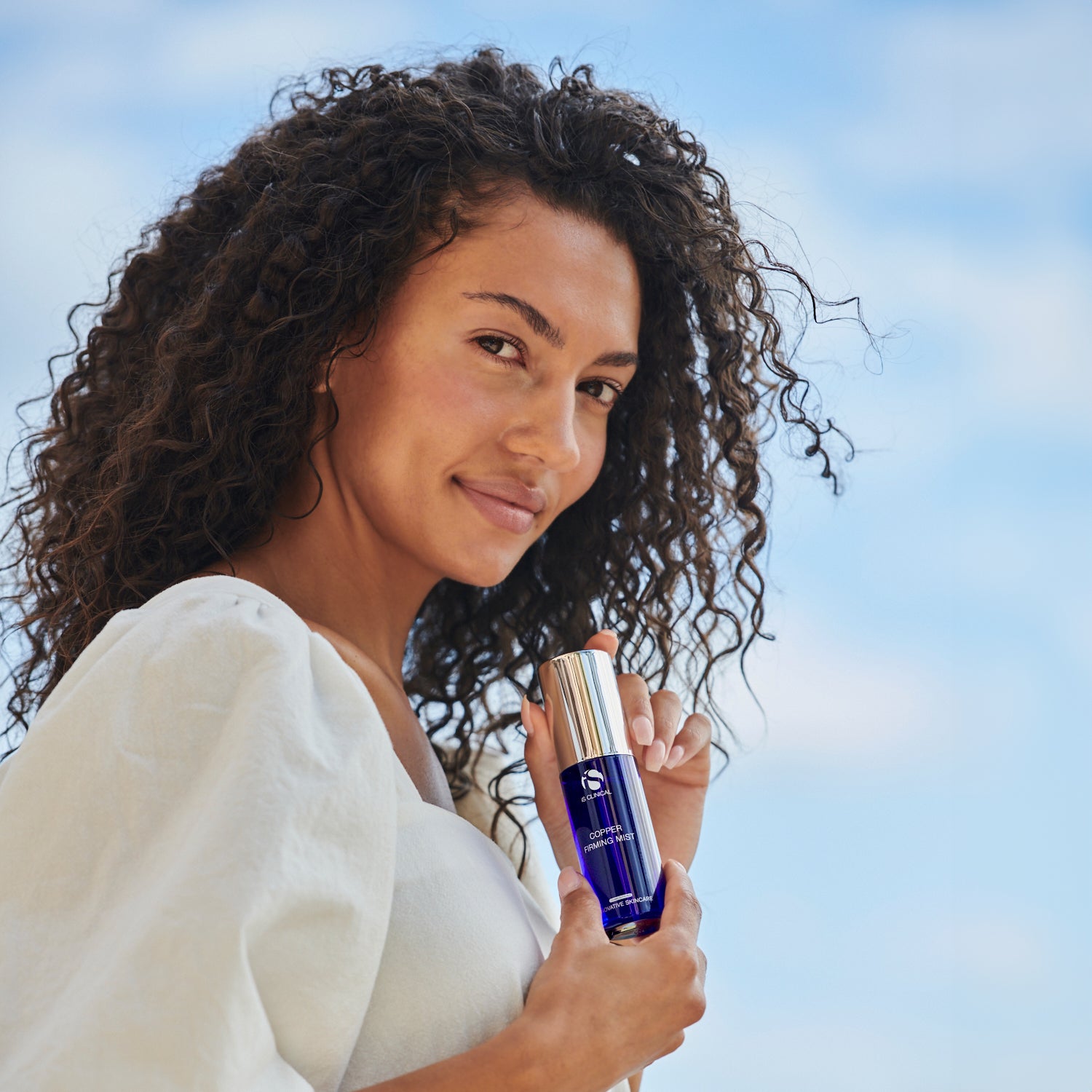 Copper Firming Mist model holding bottle outdoors, demonstrating skin hydration and firming benefits.