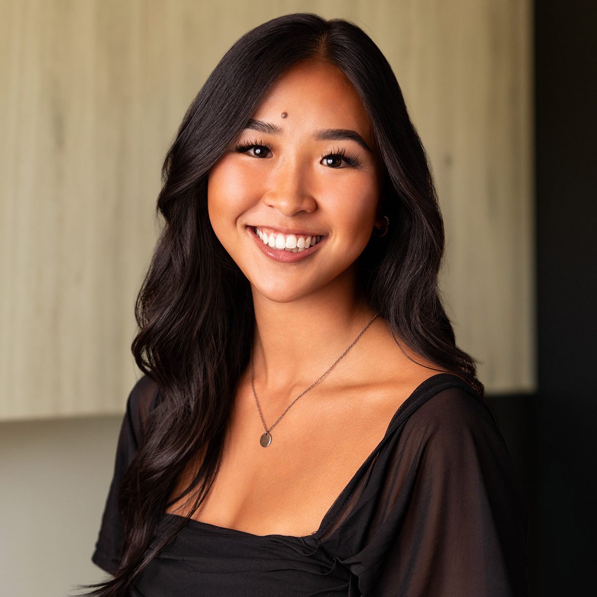 Smiling woman in a black top, showcasing MK Aesthetics services in Minnetonka Med Spa.