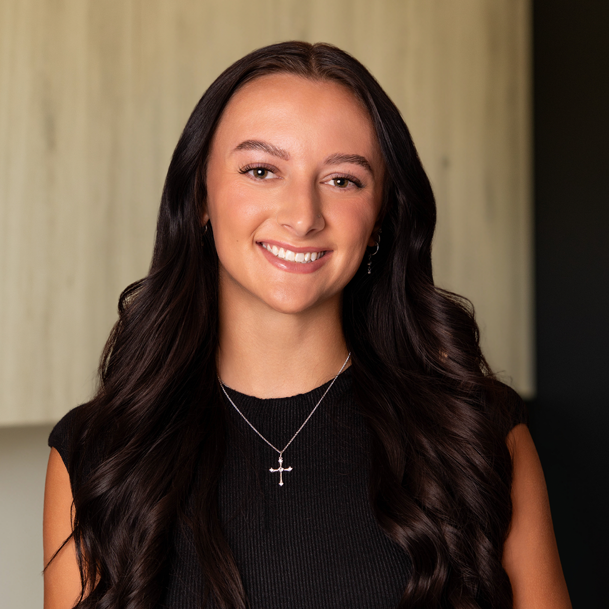 Smiling woman with long dark hair in a black top, showcasing MK Aesthetics Med Spa services in Minnetonka.