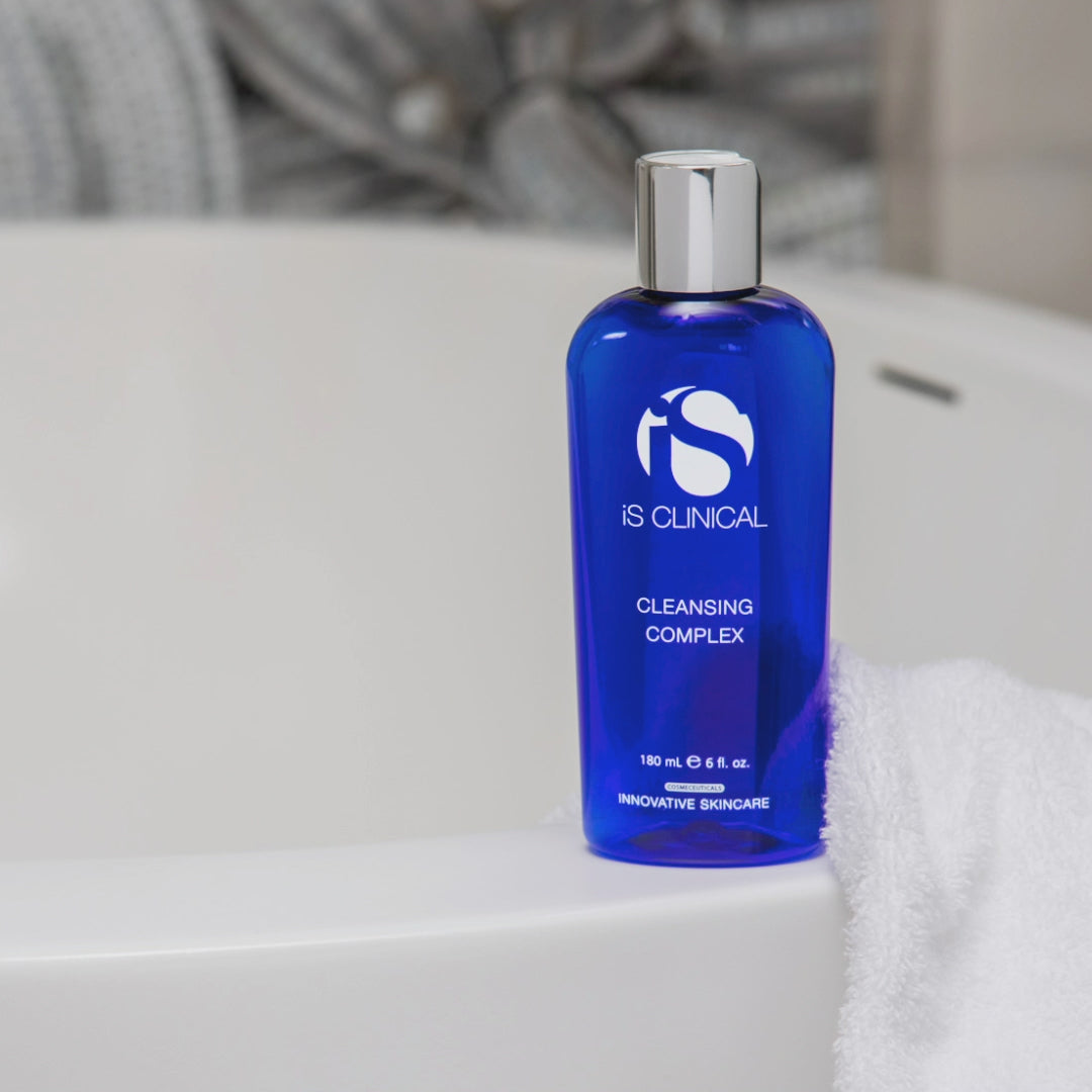 Cleansing Complex by iS Clinical in a blue bottle, placed on a bathtub edge, ideal for all skin types.