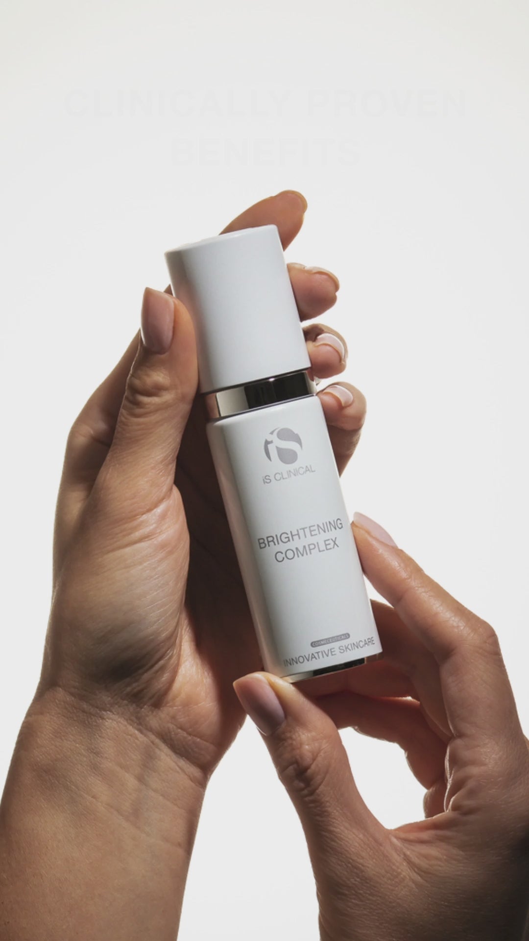 Hands holding a bottle of Brightening Complex from MK Aesthetics, showcasing the product in a soft light.