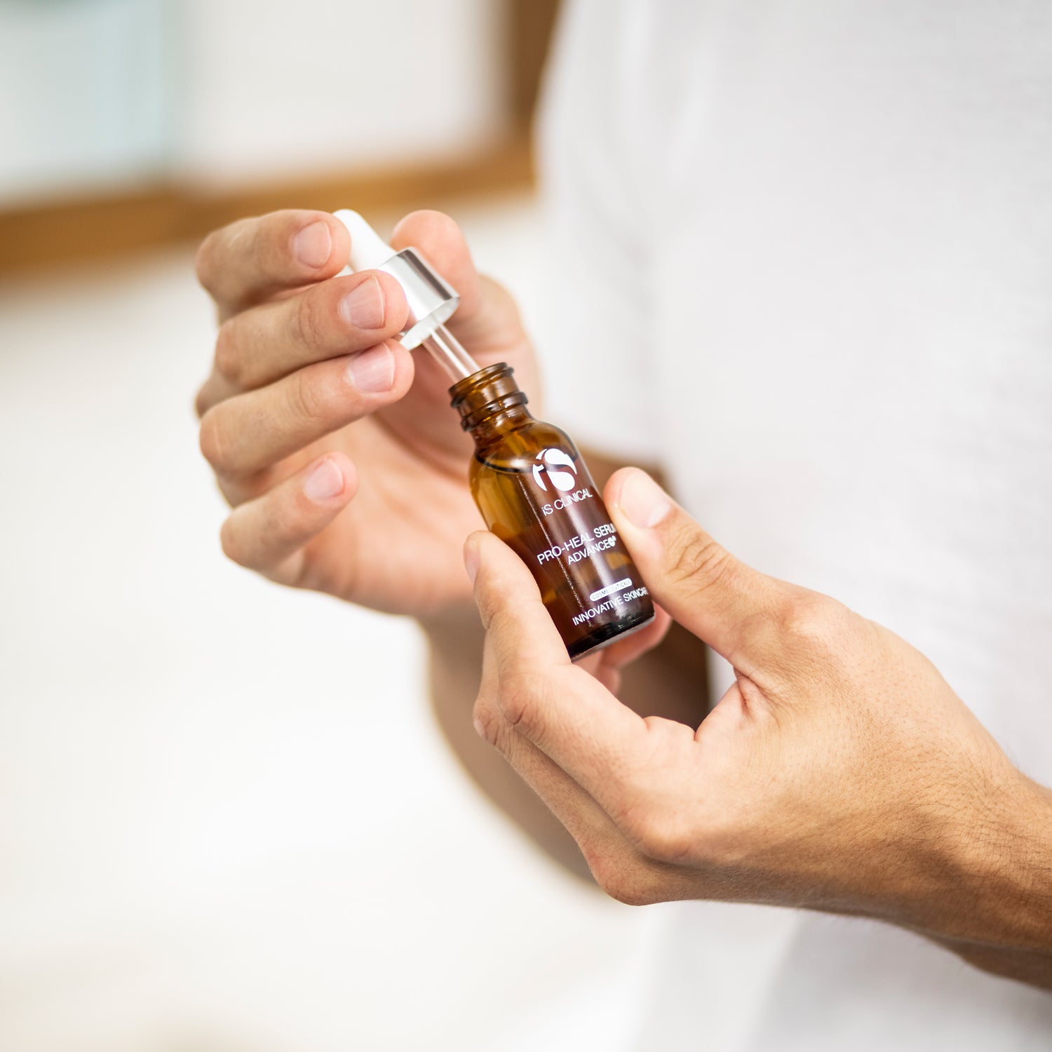 Person holding Pro-Heal Serum Advance+ dropper bottle for skincare at MK Aesthetics Spa.