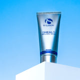 SHEALD Recovery Balm tube against a blue sky, showcasing rejuvenating formula from MK Aesthetics.