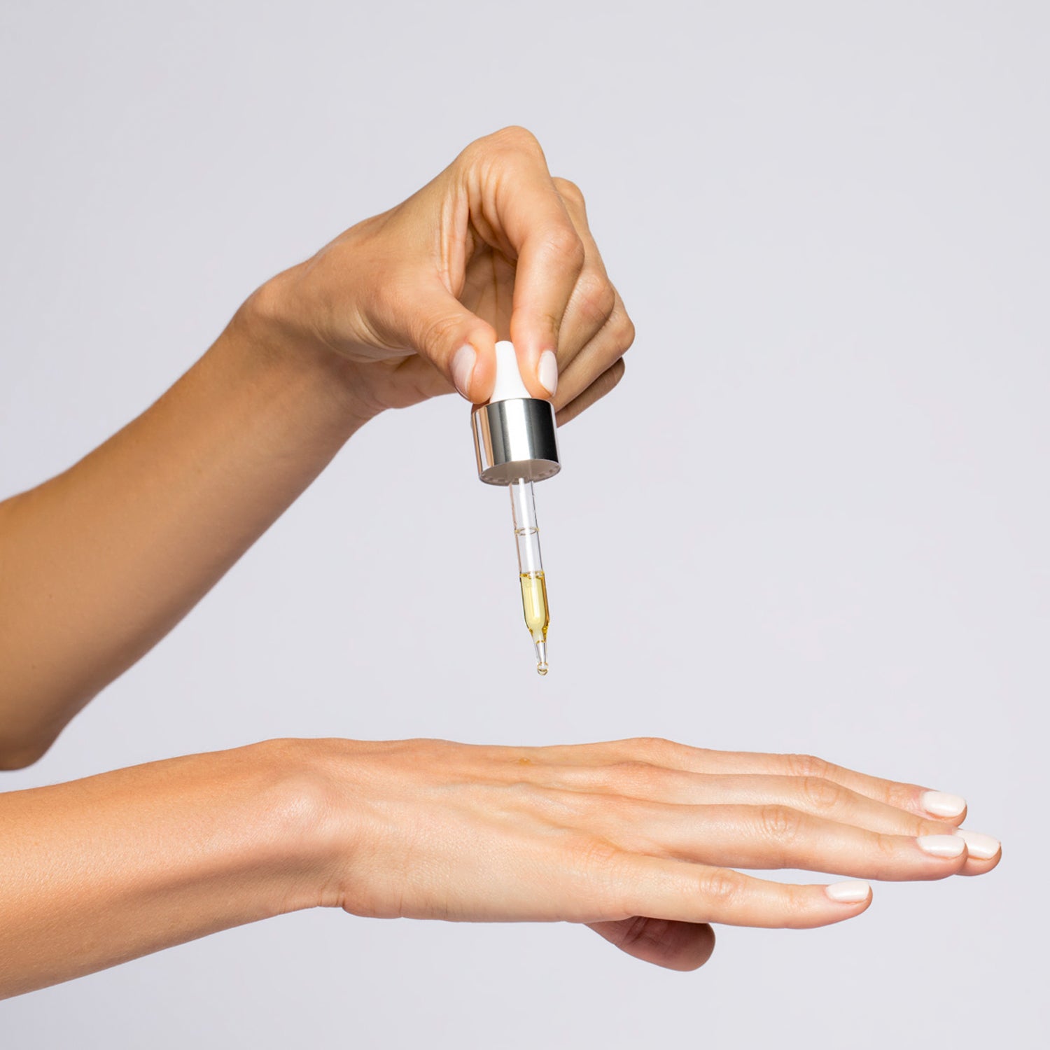 Hand holding a dropper of Super Serum Advance+ over a palm, showcasing a luxurious skincare product.