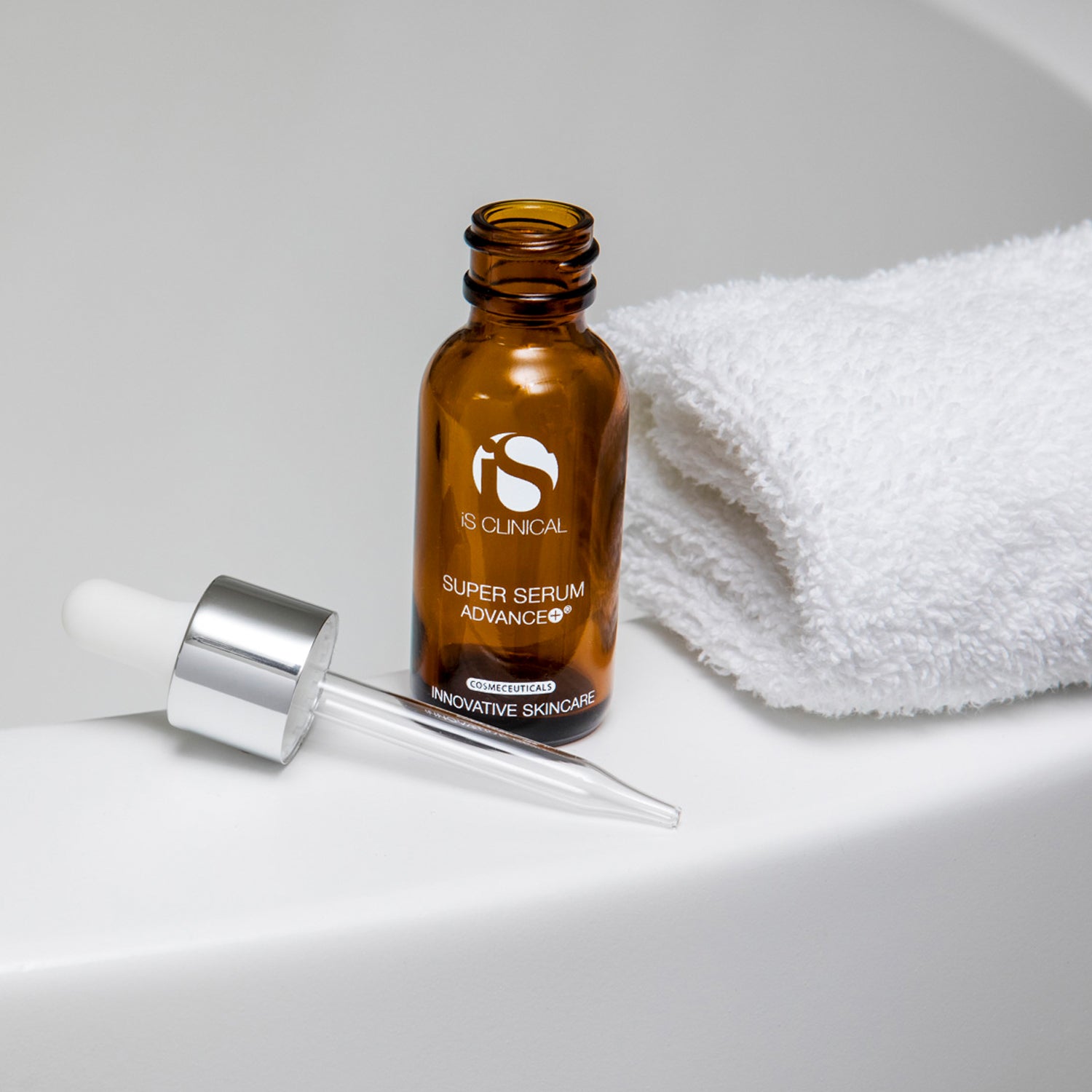 Super Serum Advance+ bottle next to a rolled towel, ideal for skincare routines at MK Aesthetics spa.